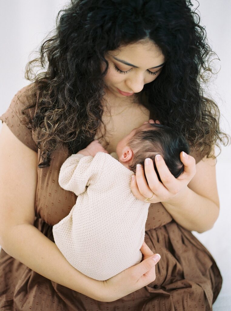 Mother with dark curly hair holding newborn baby with dark hair portrait image by Portland Newborn and Maternity Family Photographer Emilie Phillipson Photography. 