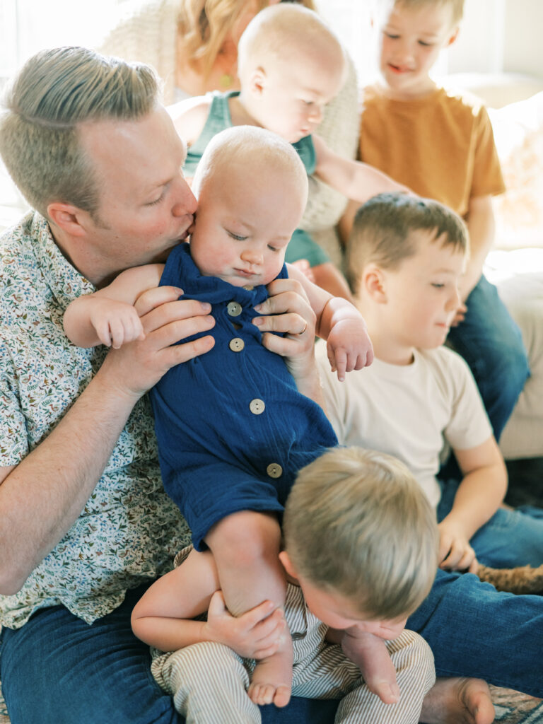 Father kisses young child's cheek amidst pile of children by Portland Family Photographer Emilie Phillipson Photography. 